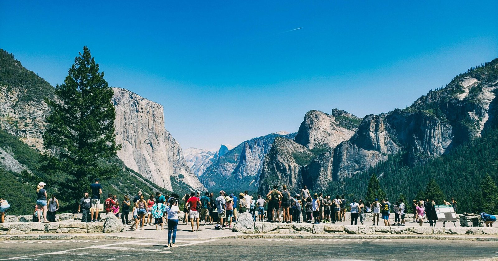 Crowds marvel at the iconic rock formations under a clear blue sky in Yosemite National Park.