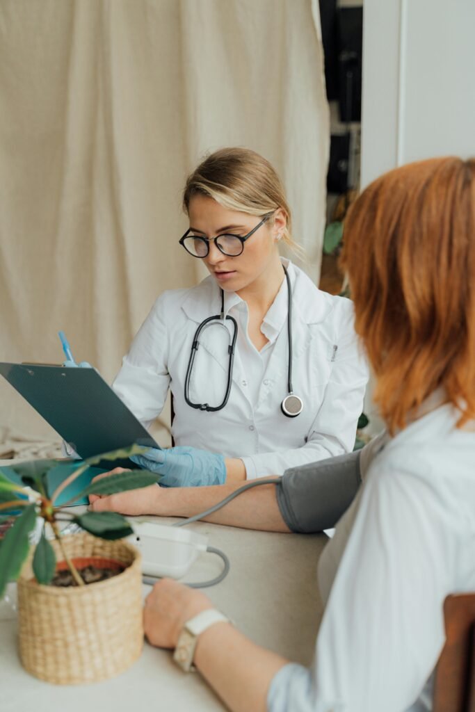 A female doctor checks a patient's blood pressure during a routine consultation in a clinic.