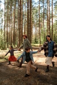 Happy family walking together in a sunlit forest, holding hands and smiling.