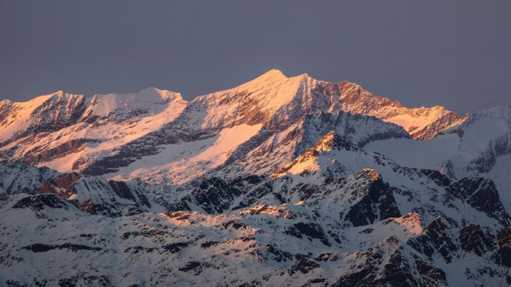 A breathtaking view of snowy mountain peaks illuminated by the golden hour sun.