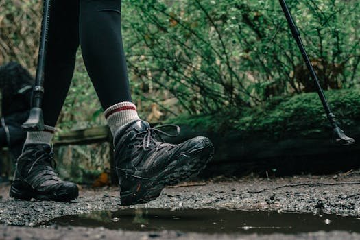 Close-up of hiker's boots splashing through a puddle on a forest trail.