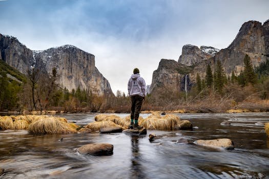 Hiker stands by Merced River in Yosemite Valley. Guide to hiking in Yosemite National Pak