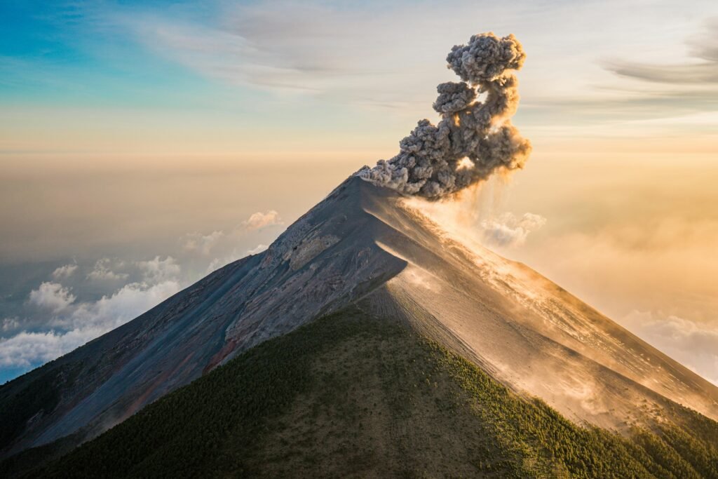 Smoke billows from Acatenango Volcano, Guatemala, captured in a breathtaking aerial view at sunset.