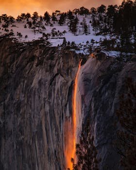 Sunset glow creates a fiery waterfall effect on a snowy cliff Yosemite National Park.