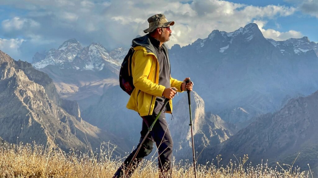 An adult male hiker with trekking poles explores the mountain landscape.